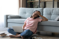 woman sitting on the floor falling asleep at her laptop