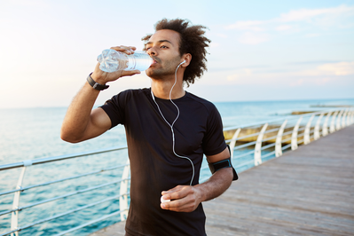 man drinking water while running on pier